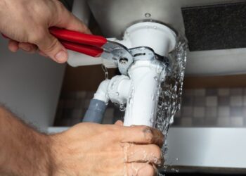 Close-up Of Male Plumber Fixing White Sink Pipe With Adjustable Wrench
